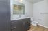 Modern bathroom featuring sleek dark wood cabinetry, a spacious countertop with an integrated sink, and elegant fixtures under soft lighting, ideal for a contemporary lifestyle.