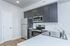 Modern kitchen with sleek stainless steel appliances, dark cabinetry, and a polished white countertop.
