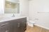 Bright and modern bathroom featuring sleek cabinetry, a spacious countertop with an elegant sink, and a pristine toilet, creating a serene spa-like retreat.