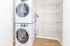 Modern laundry room with a sleek stacked washer and dryer and ample wire shelving for storage.