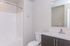 Modern bathroom featuring a sleek vanity, large mirror, and a pristine shower area.