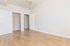 Bright and spacious bedroom with sleek wooden flooring and modern closet space, perfect for stylish living.