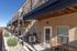 Elegant apartment exterior with a spacious patio, charming landscaping, and modern balconies under a clear blue sky.