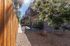 Charming apartment exterior with a sunlit patio, lush greenery, and a stylish wooden fence for privacy and tranquility.