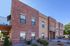 Charming brick apartment building with modern design and inviting landscape under a clear blue sky.