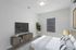 Modern bedroom with sleek design featuring a cozy bed, stylish nightstand, elegant TV unit, and vibrant indoor plant for a refreshing ambiance.
