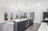 Modern kitchen with sleek dark cabinetry, elegant white countertops, and ample natural light from large glass doors leading to a beautiful balcony view.