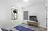 Bright and modern bedroom featuring chic decor, stylish artwork, and natural light from the window, perfect for relaxation.