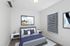 Elegant bedroom with modern decor, featuring a cozy bed, stylish nightstands, and contemporary artwork. Abundant natural light filters through sleek blinds, enhancing the serene ambiance.