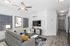 Modern living room with sleek decor, featuring a cozy sofa, stylish wall art, and a mounted flat-screen TV, accented by ample natural light from large windows.