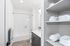 Bright and modern bathroom with elegant shelving and neatly folded towels, featuring a stylish vanity and a spacious shower area.