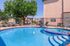 Inviting outdoor pool area with vibrant blue water, surrounded by lounge chairs and lush greenery, perfect for relaxation and enjoyment.