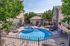 Inviting outdoor area showcasing a charming circular pool with adjacent hot tub, surrounded by comfortable lounge chairs and lush greenery, perfect for relaxation and leisure.