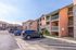 Inviting apartment complex with modern stone accents, ample parking, and accessible walkways under a clear blue sky.