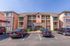 Charming apartment complex featuring rustic stone accents, a warm color palette, and ample parking.
