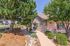 Charming cottage-style home with rustic stone facade, set among lush trees and manicured landscaping.