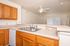 Bright and inviting kitchen with modern double sink, wooden cabinetry, and open layout featuring a ceiling fan and ample counter space.