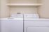 Contemporary laundry room with a sleek washer and dryer set, complemented by a convenient overhead shelf.