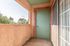 Inviting apartment balcony with stylish green door and scenic tree-lined view, offering a serene outdoor space.