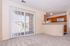 Bright living space with plush carpet, sliding glass doors leading to a scenic view, and an adjacent kitchen featuring wooden cabinets and modern appliances.