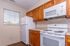 Bright and modern kitchen with sleek appliances, including a white microwave and stove, complemented by warm wooden cabinets and natural light from a large window.