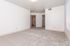 Bright, open room with plush carpeting, neutral walls, and ample natural light from large windows, perfect for versatile living arrangements.