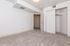 Bright and spacious bedroom with plush carpet and open closet, perfect for modern living.