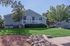 Charming house with a lush green lawn, welcoming porch, and beautiful trees, offering a serene and attractive exterior.