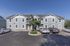Charming apartment building with a modern facade, ample parking, and lush landscaping under a clear blue sky.