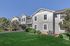 Charming apartment complex with manicured lawns, featuring modern architecture and lush greenery under a clear blue sky.