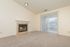 Inviting living room with plush carpet, modern fireplace, and large sliding door opening to a serene balcony.