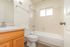 Bright and airy modern bathroom with sleek fixtures, elegant wood cabinetry, and pristine white tiles.