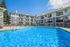 Inviting apartment complex with a sparkling pool, sun loungers, and modern balconies, perfect for relaxation and leisure.