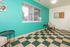 Vibrant, modern room with teal accent wall, stylish checkered flooring, and cozy seating area, perfect for relaxation or a creative workspace.
