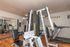 Inviting fitness center featuring modern equipment including a weight machine and treadmill, with sleek wood flooring and motivational decor.
