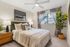 Inviting modern bedroom with cozy decor, featuring a stylish bed, elegant lamps, and a vibrant plant by the window.