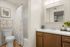 Contemporary bathroom with elegant wood cabinetry, stylish patterned shower curtain, and modern fixtures.