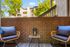 Charming outdoor patio with cozy wicker chairs, vibrant cushions, and a peaceful garden view, perfect for relaxation.