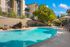 Luxurious apartment complex with inviting outdoor pool, stylish lounge chairs, and vibrant umbrellas under a clear blue sky.