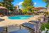 Inviting poolside oasis featuring chic lounge chairs and vibrant umbrellas, surrounded by lush greenery under a bright blue sky.