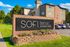 Charming Sofi Belmar apartment homes sign with vibrant landscaping, set against a backdrop of modern architecture, offering welcoming and serene living.