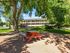 Inviting apartment complex surrounded by lush greenery, featuring outdoor picnic tables and a colorful playground for family-friendly living.