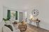 Inviting living room featuring a plush sofa, vibrant green curtains, and a stylish wall clock, perfect for relaxation and entertaining.