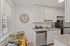 Bright and modern kitchen with sleek white cabinetry, stainless steel appliances, and a cozy nook featuring a stylish dining setup under a classic wall clock.