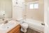 Elegant bathroom with modern fixtures, featuring a white bathtub, spacious vanity, and stylish wood flooring.