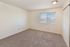 Bright bedroom with plush carpeting, featuring a large window offering stunning mountain views, perfect for relaxation.