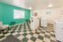 Bright and inviting laundry room with modern washing machines, vibrant teal accent wall, and cozy seating area.
