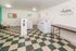Welcoming laundry room with modern washers, checkered flooring, and cozy seating, ideal for convenient living.