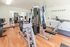 Bright and inviting apartment gym with modern equipment, including a treadmill and weight machines on sleek wooden flooring.