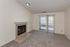 Light-filled living room with plush carpeting, a cozy fireplace, and sliding glass doors leading to a serene balcony view.